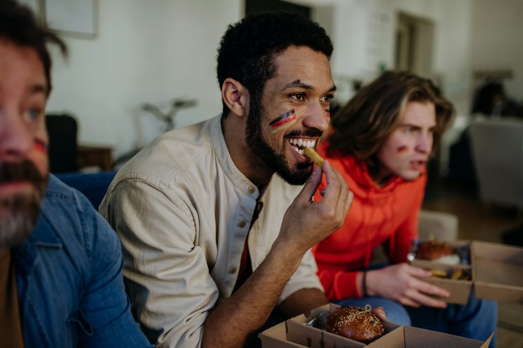 Nervous football fans friends staring at TV and watching football match at home