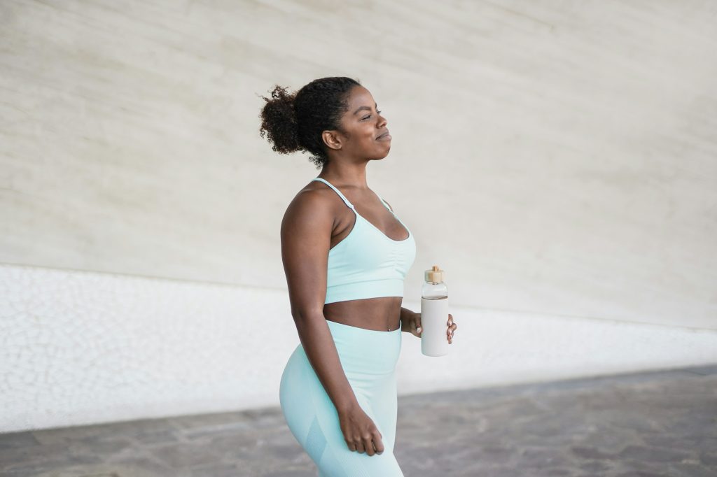 Young african woman drinking water after sport workout