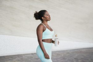 Young african woman drinking water after sport workout